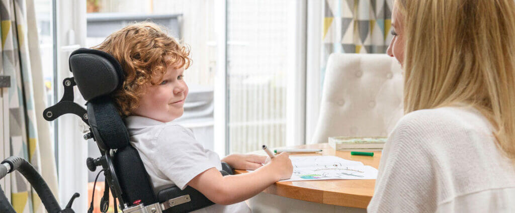 Bot in a wheelchair at a table writing