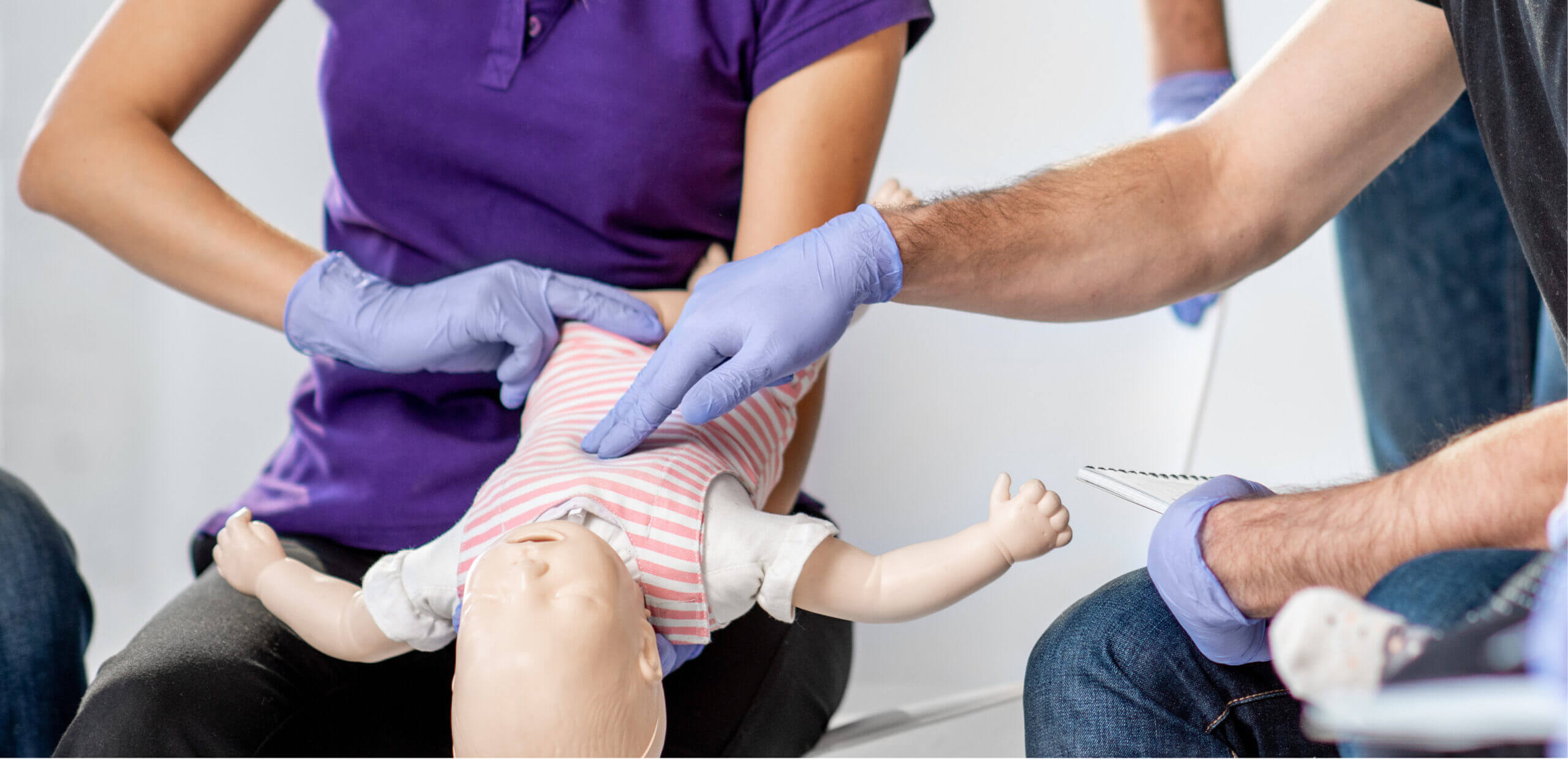 Health worker demonstrating life saving techniques on a dummy that looks like a baby