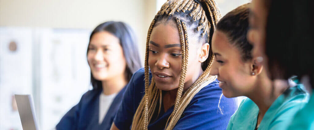Group of healthcare workers looking at computers and learning