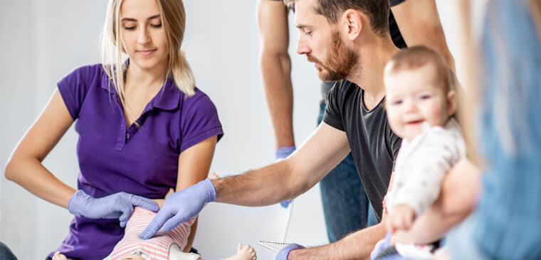 Health worker demonstrating life saving techniques on a dummy that looks like a baby